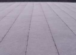 Flat surfaced roof coating. Heating and melting bitumen roofing felt background pattern.